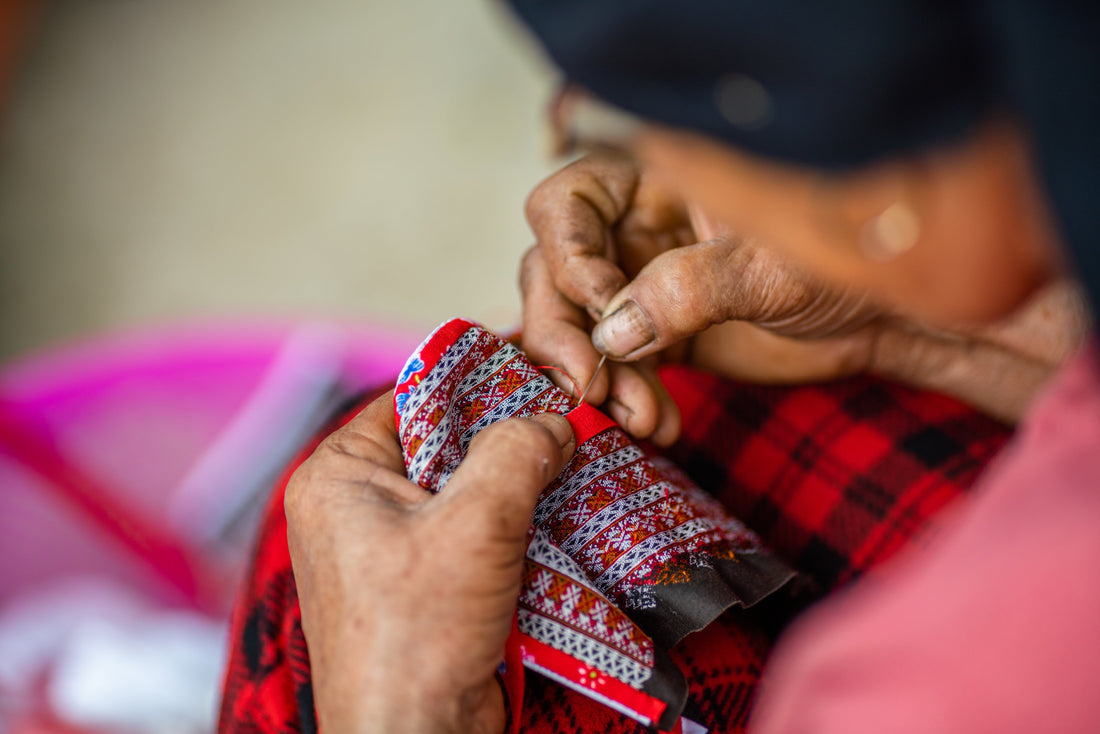 Close-up of hands sewing traditional Andean textile patterns by hand