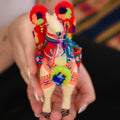 Colorful embroidered llama toy held in hands with a blurred background