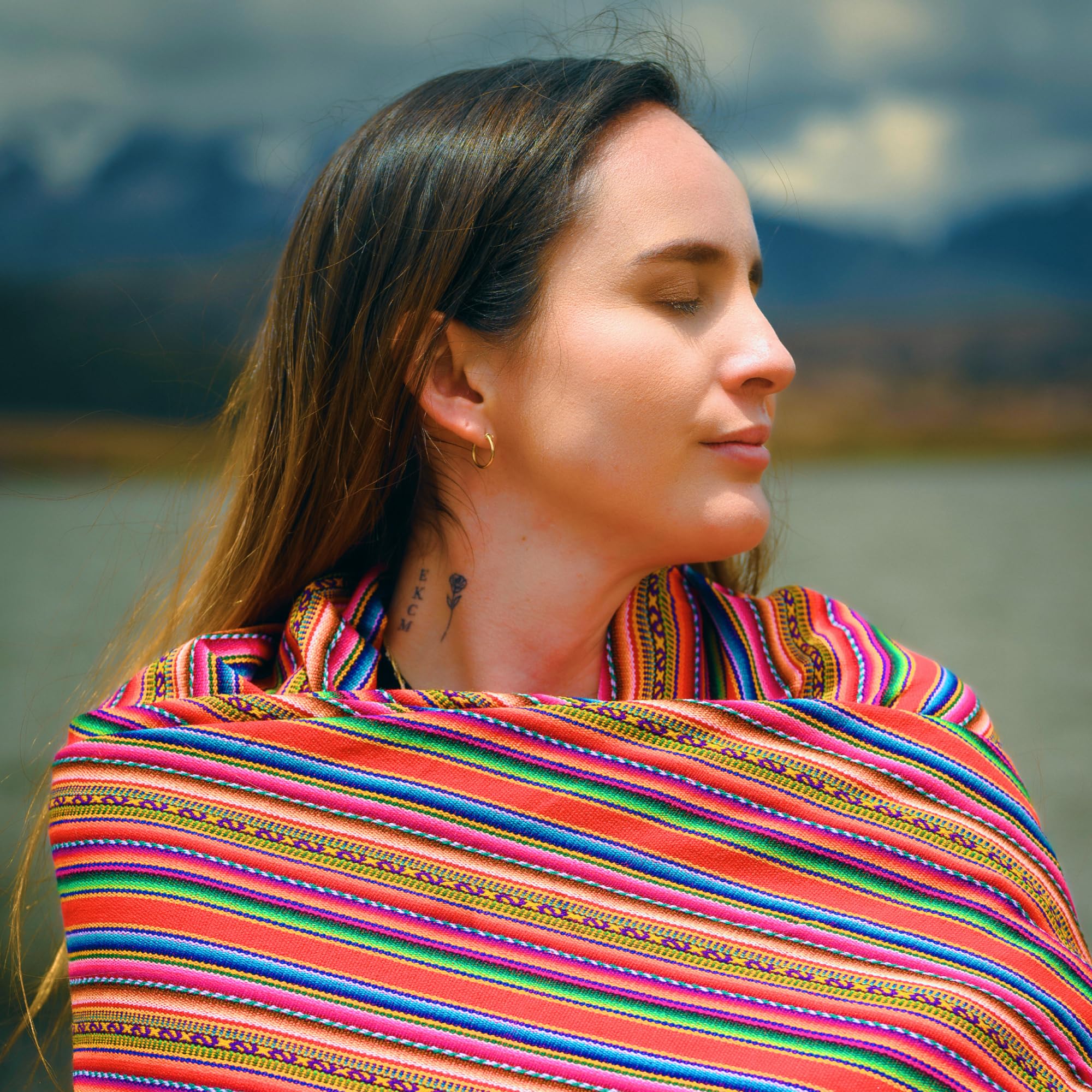 Woman wearing a colorful striped shawl with a blurred natural background