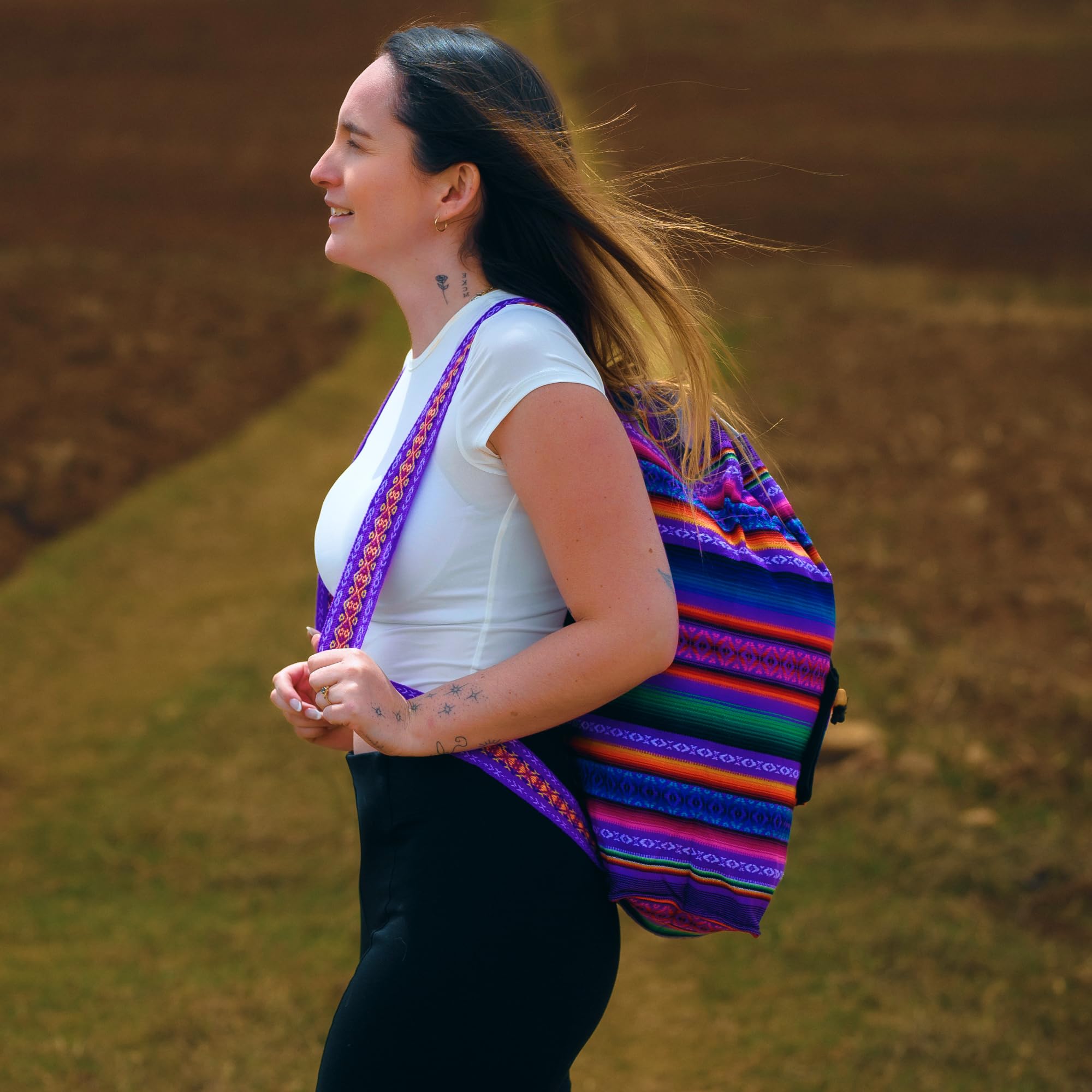 Woman with a colorful backpack walking outdoors on a grassy path