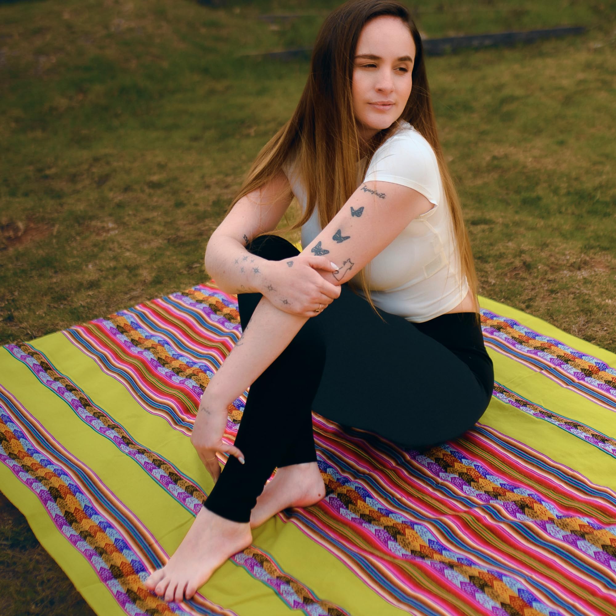 Woman sitting on a colorful striped blanket outdoors