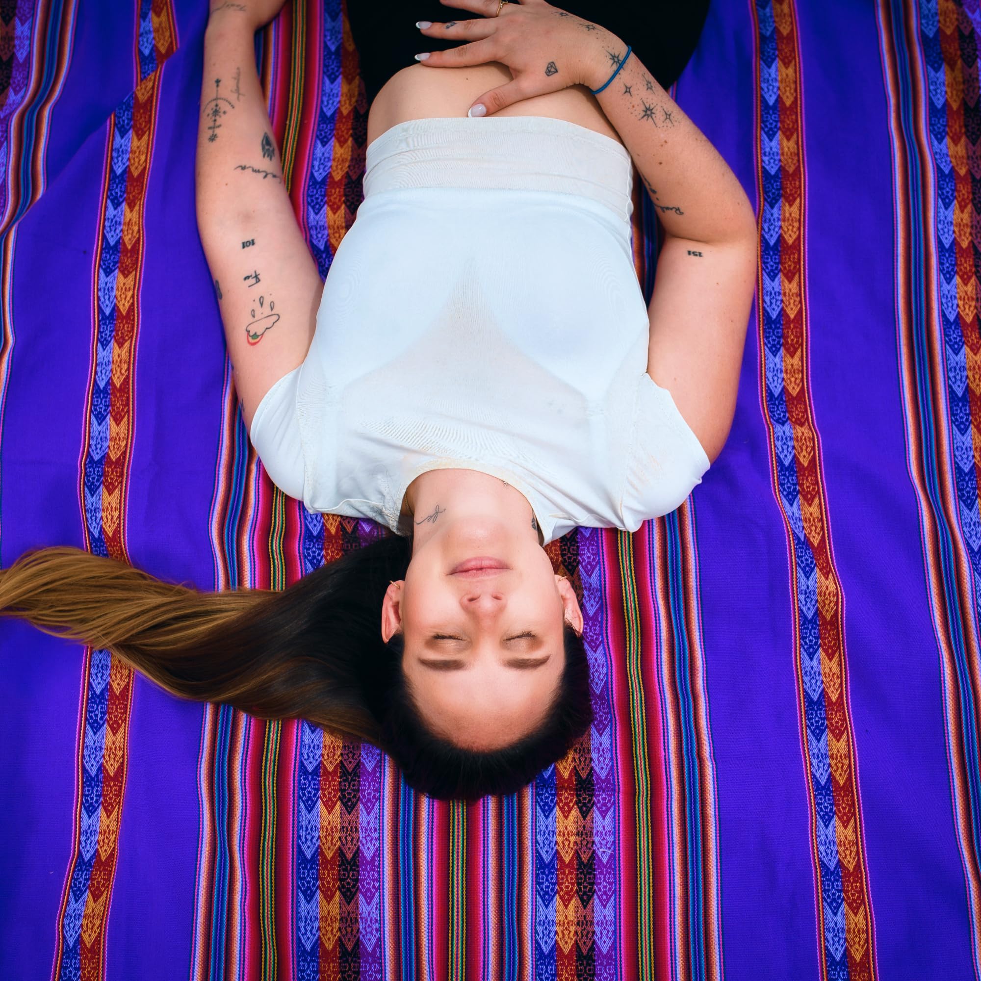 Person lying on a colorful striped fabric with a purple background