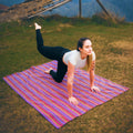 Woman practicing yoga on a colorful striped mat outdoors