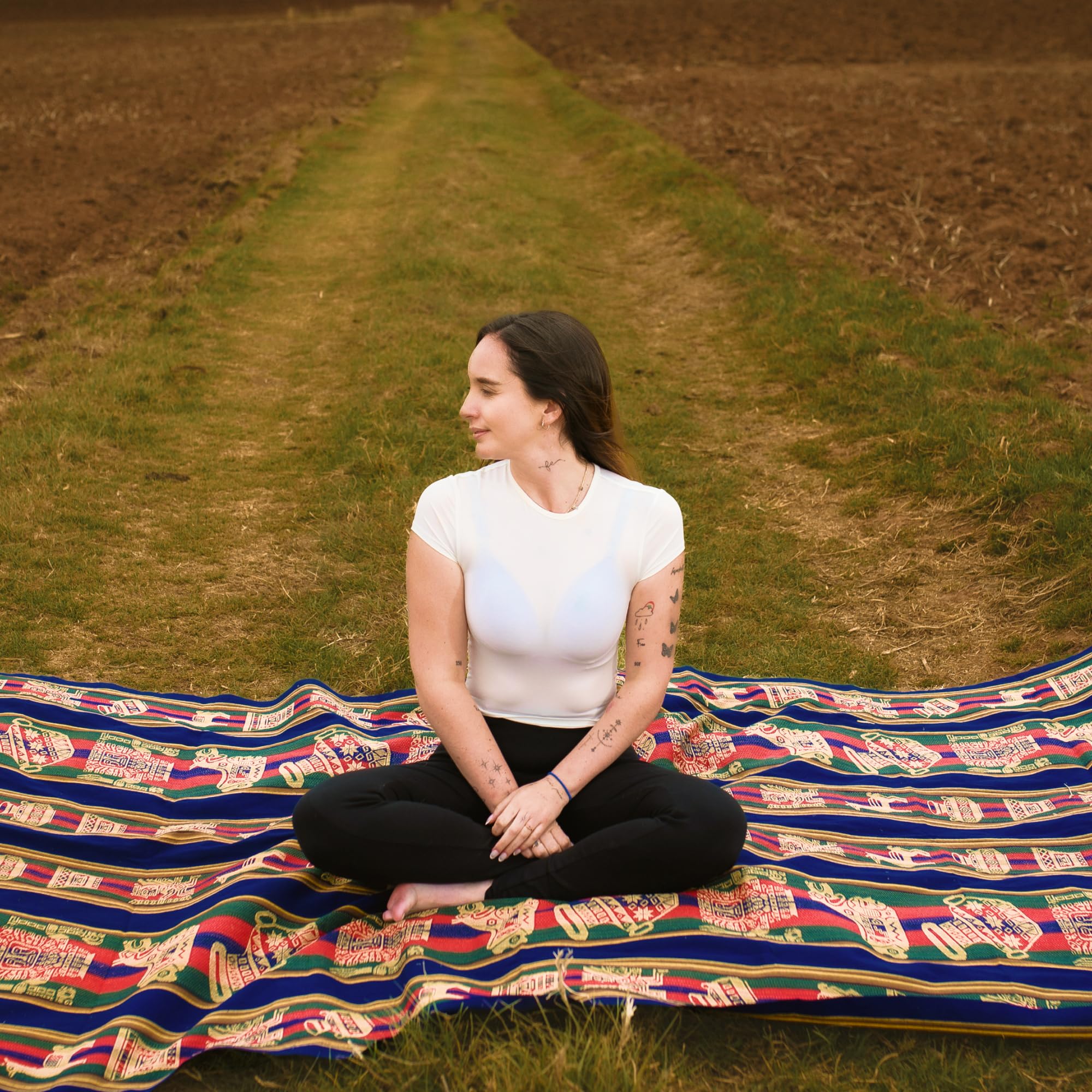 Woman sitting on a colorful blanket in a field