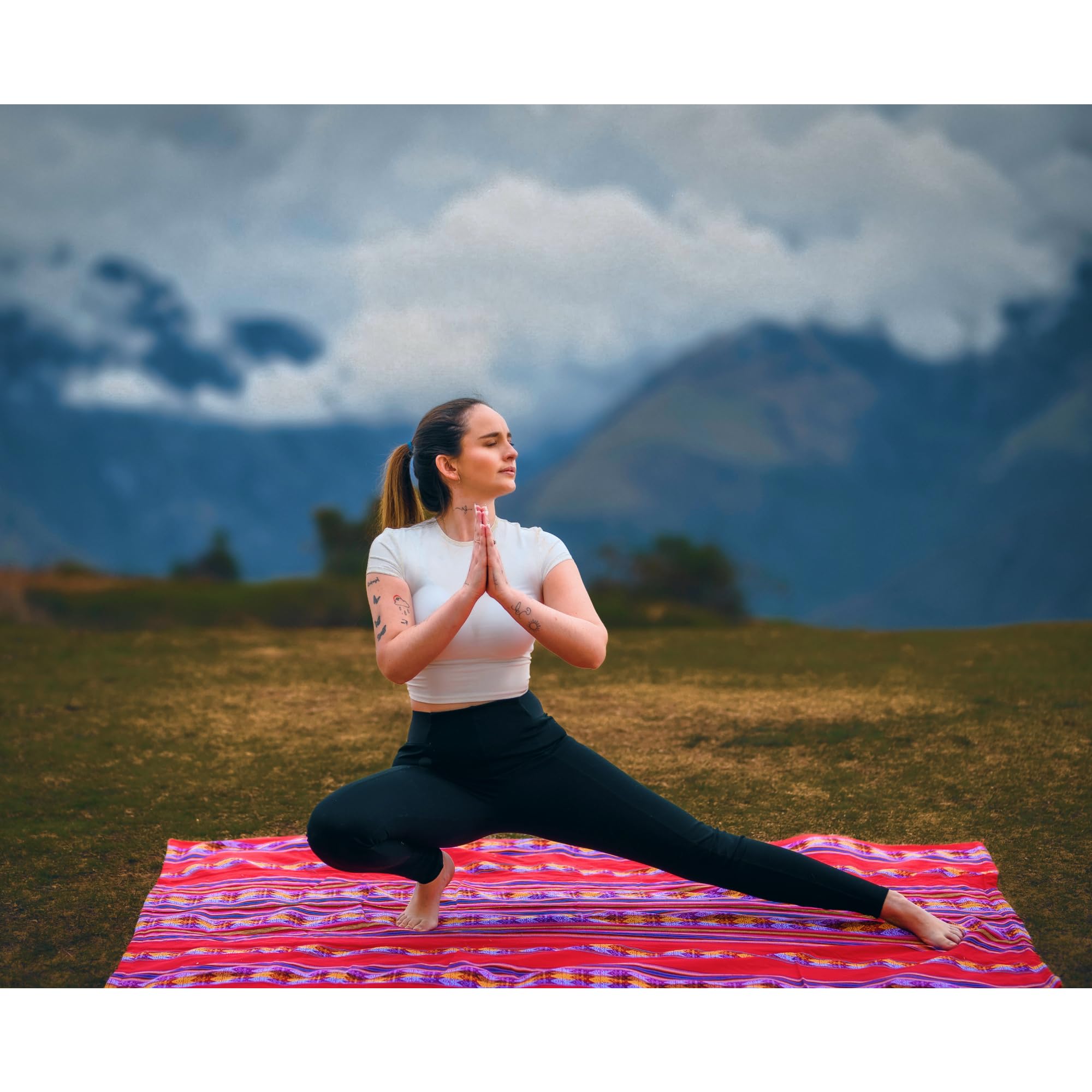 Woman practicing yoga on a colorful mat with mountains in the background