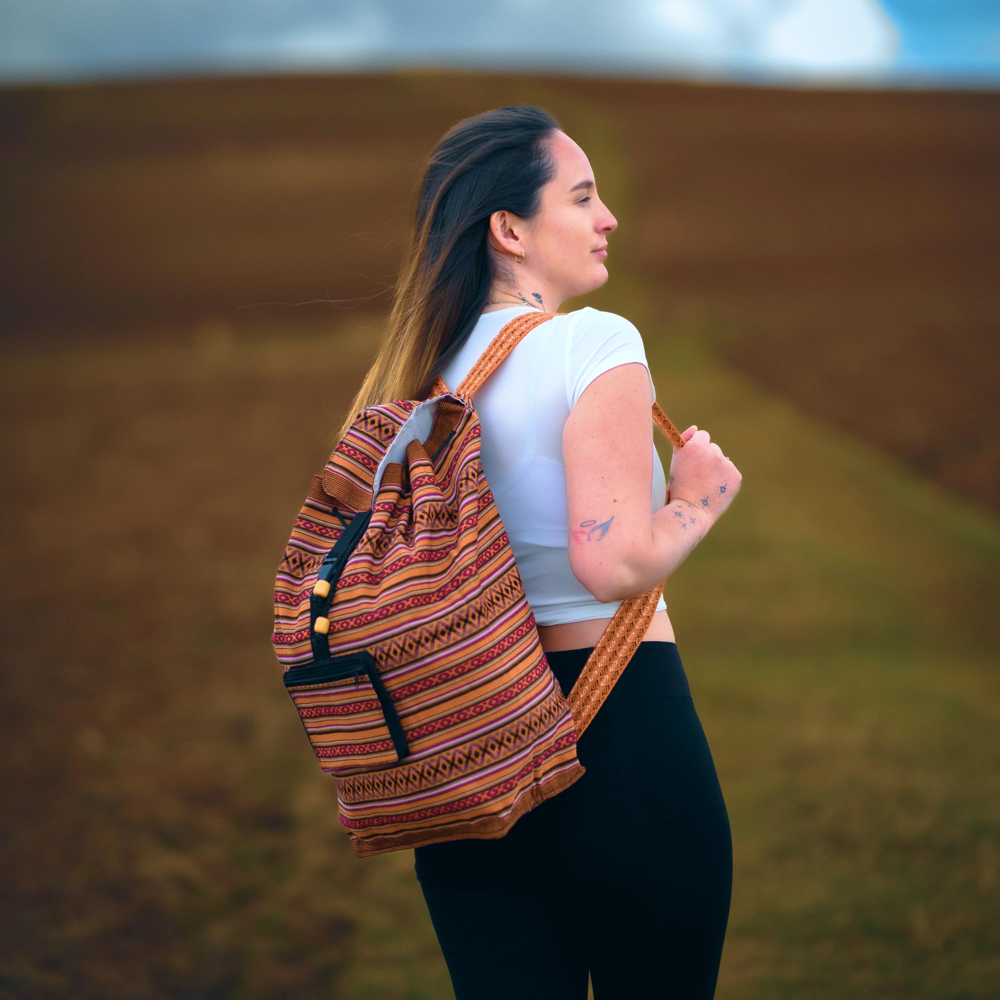 Woman with a patterned backpack standing outdoors with a blurred natural background