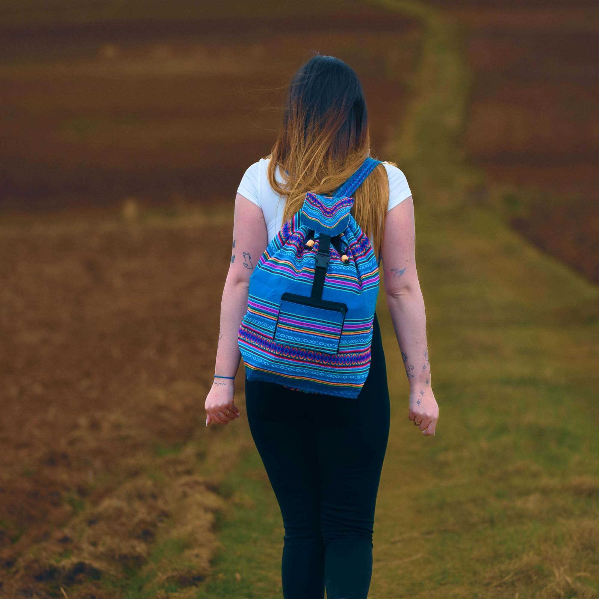 Person walking on a path with a colorful striped backpack