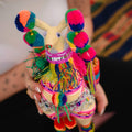 Colorful handcrafted llama figure held by a person with a blurred background