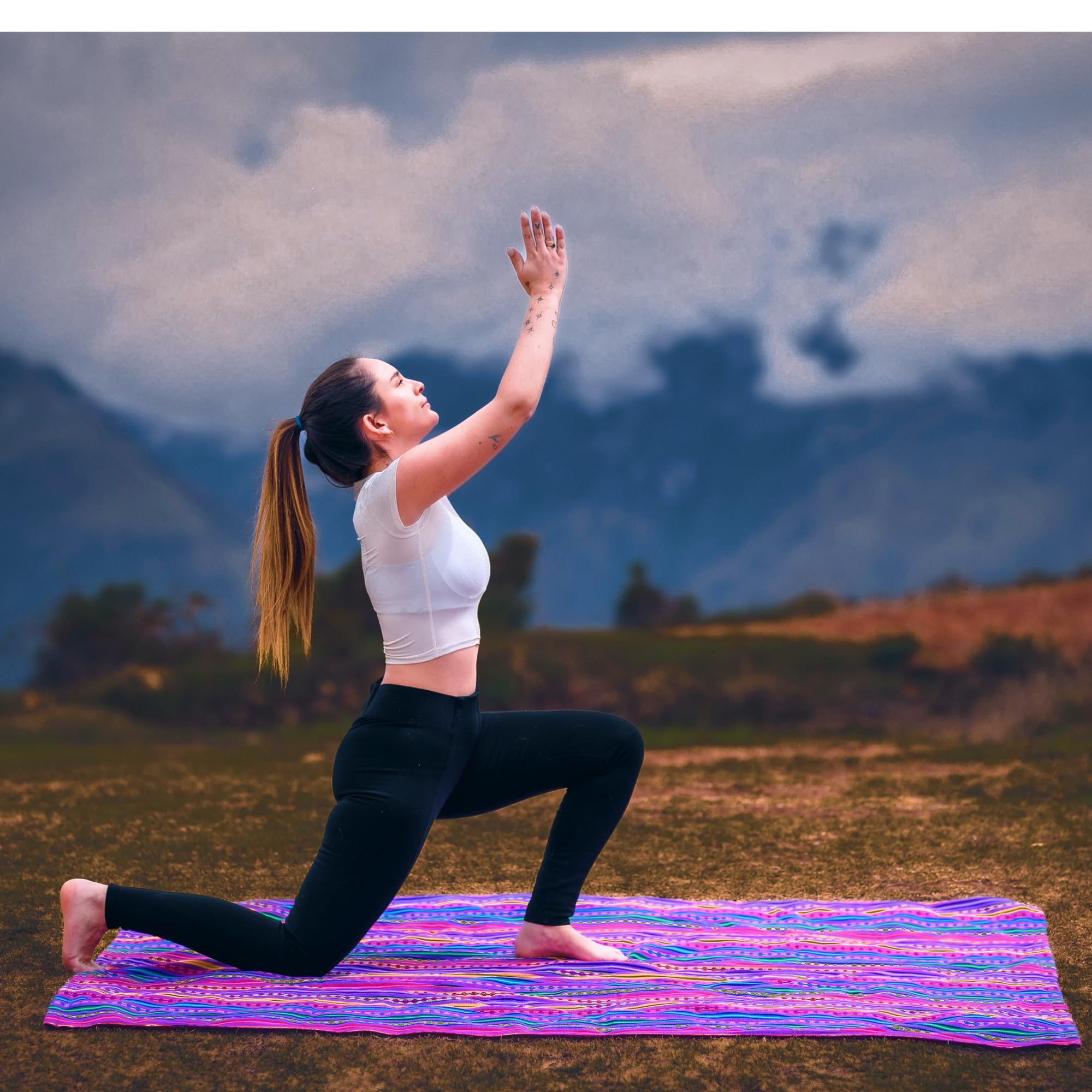 Woman practicing yoga on a colorful mat with mountains in the background
