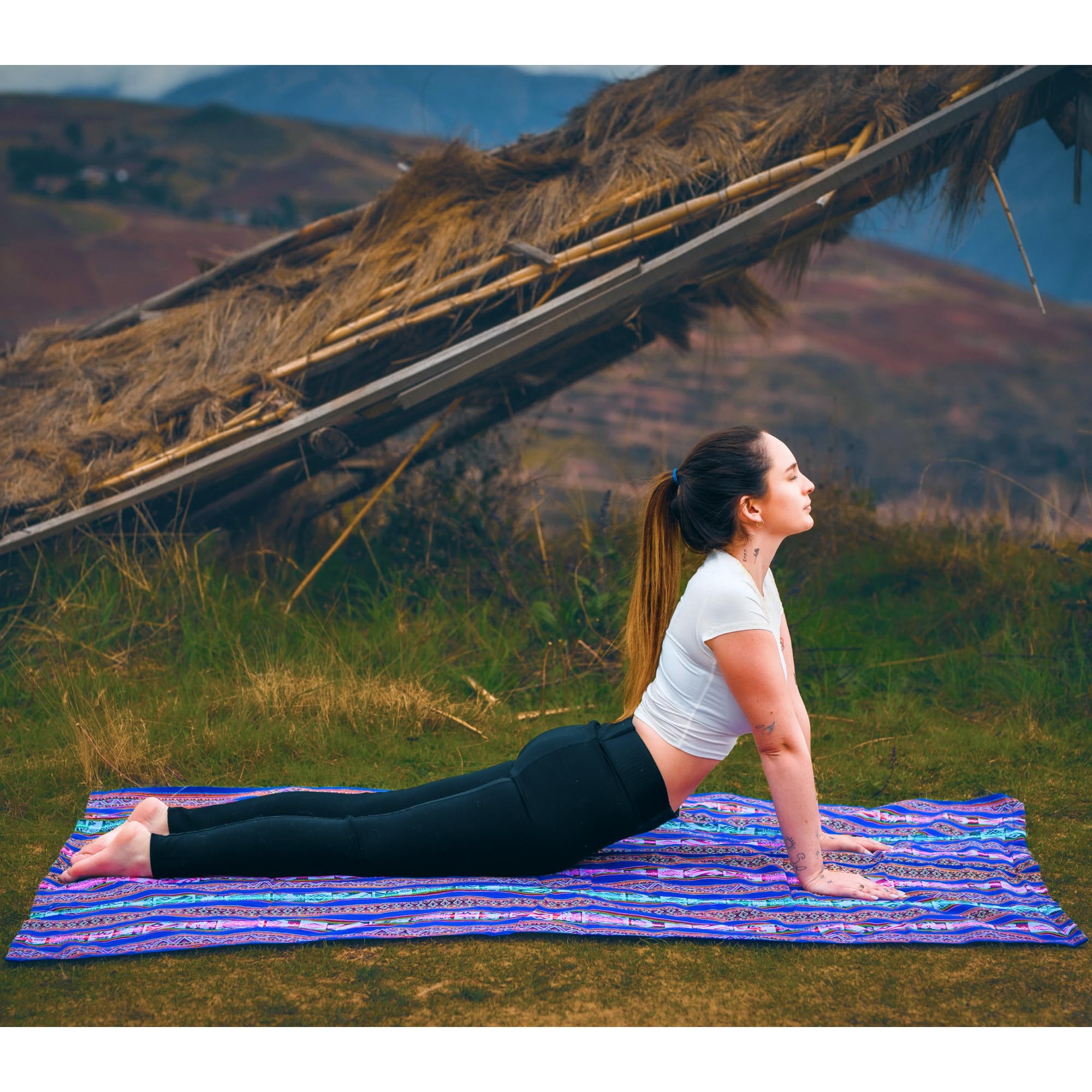 Woman practicing yoga on a mat outdoors with mountains in the background