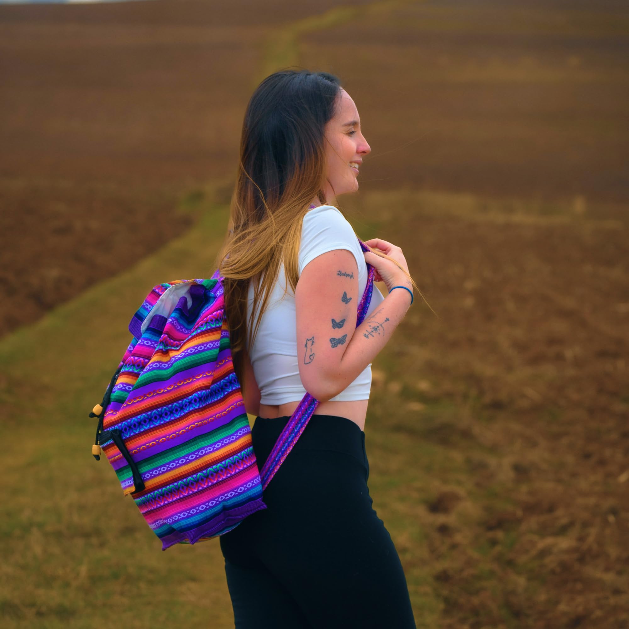 Woman with a colorful backpack standing in a field