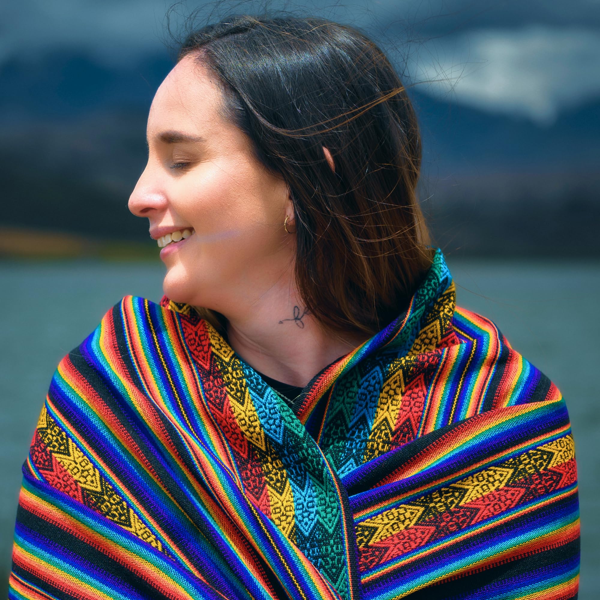 Woman wearing a colorful traditional garment with a body of water and mountains in the background