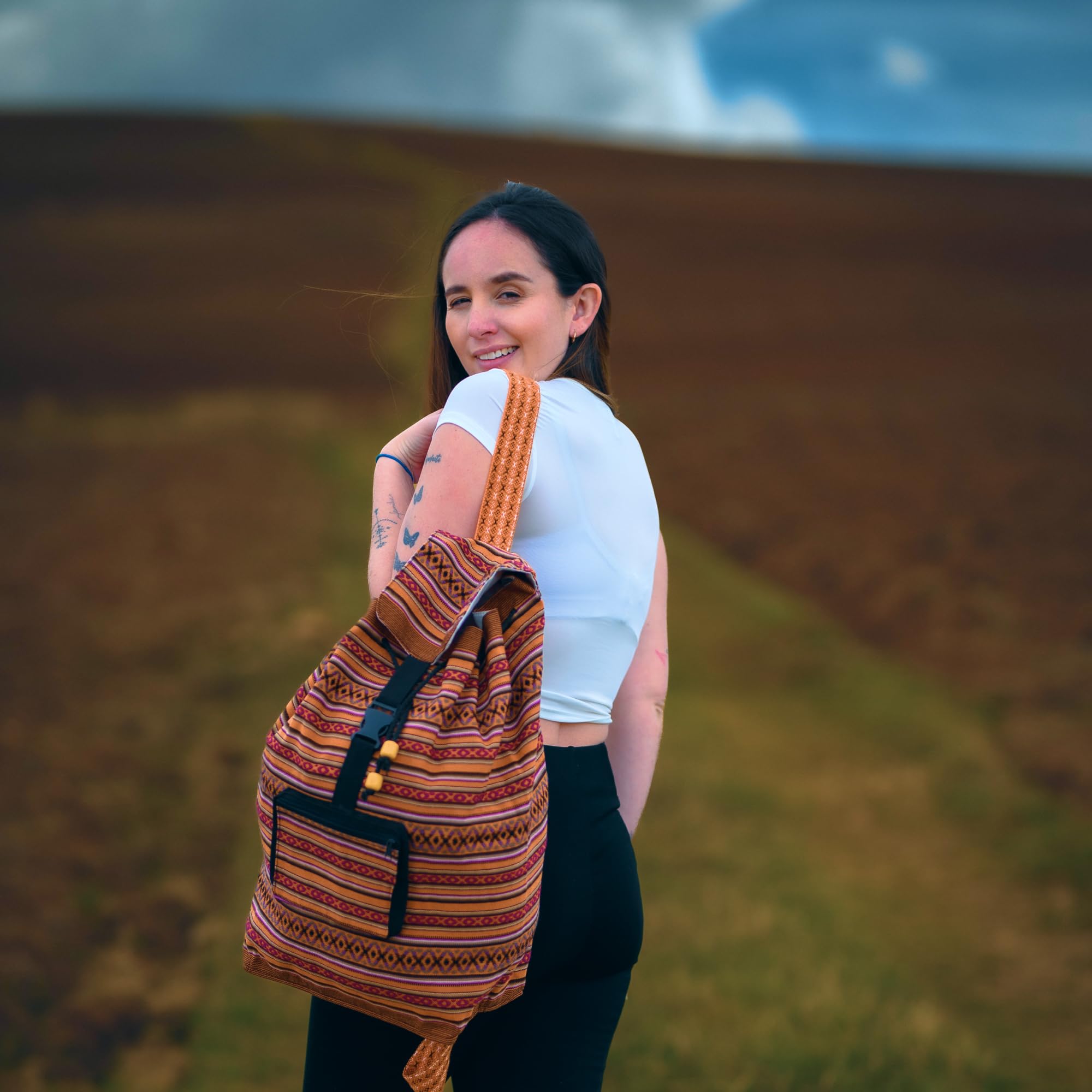 Woman with a striped backpack standing in a field with blurred background