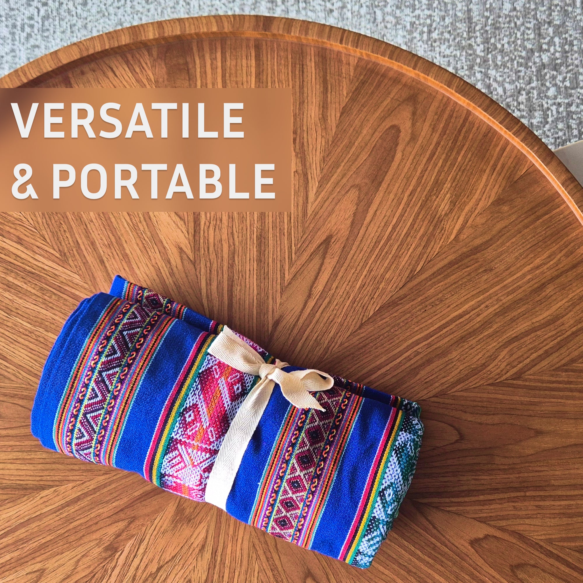Colorful patterned blanket on a wooden table with 'VERSATILE & PORTABLE' text.
