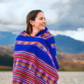 Woman wrapped in a colorful patterned blanket with mountains in the background