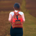 Person wearing a red and orange patterned backpack in a natural setting