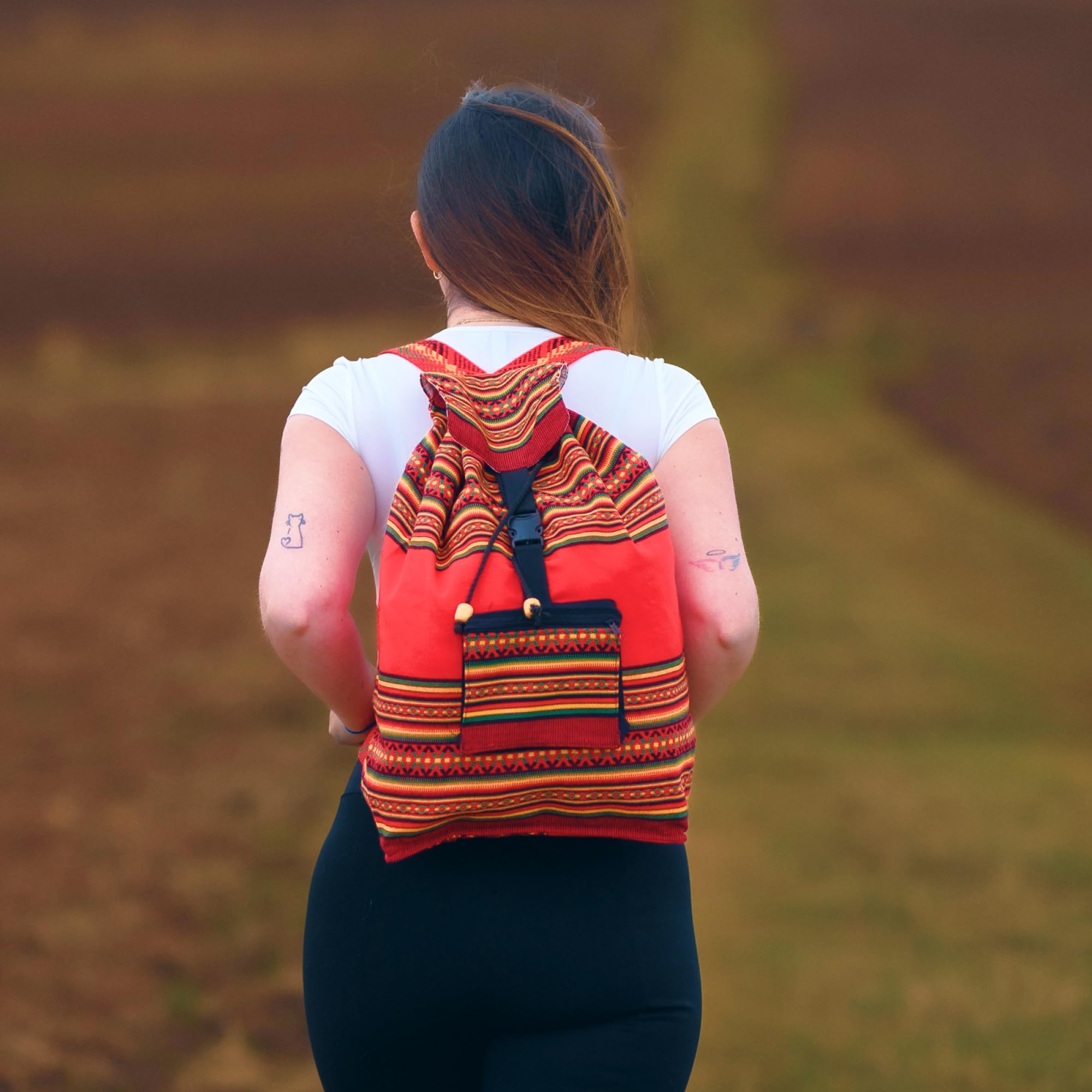 Person wearing a red and orange patterned backpack in a natural setting
