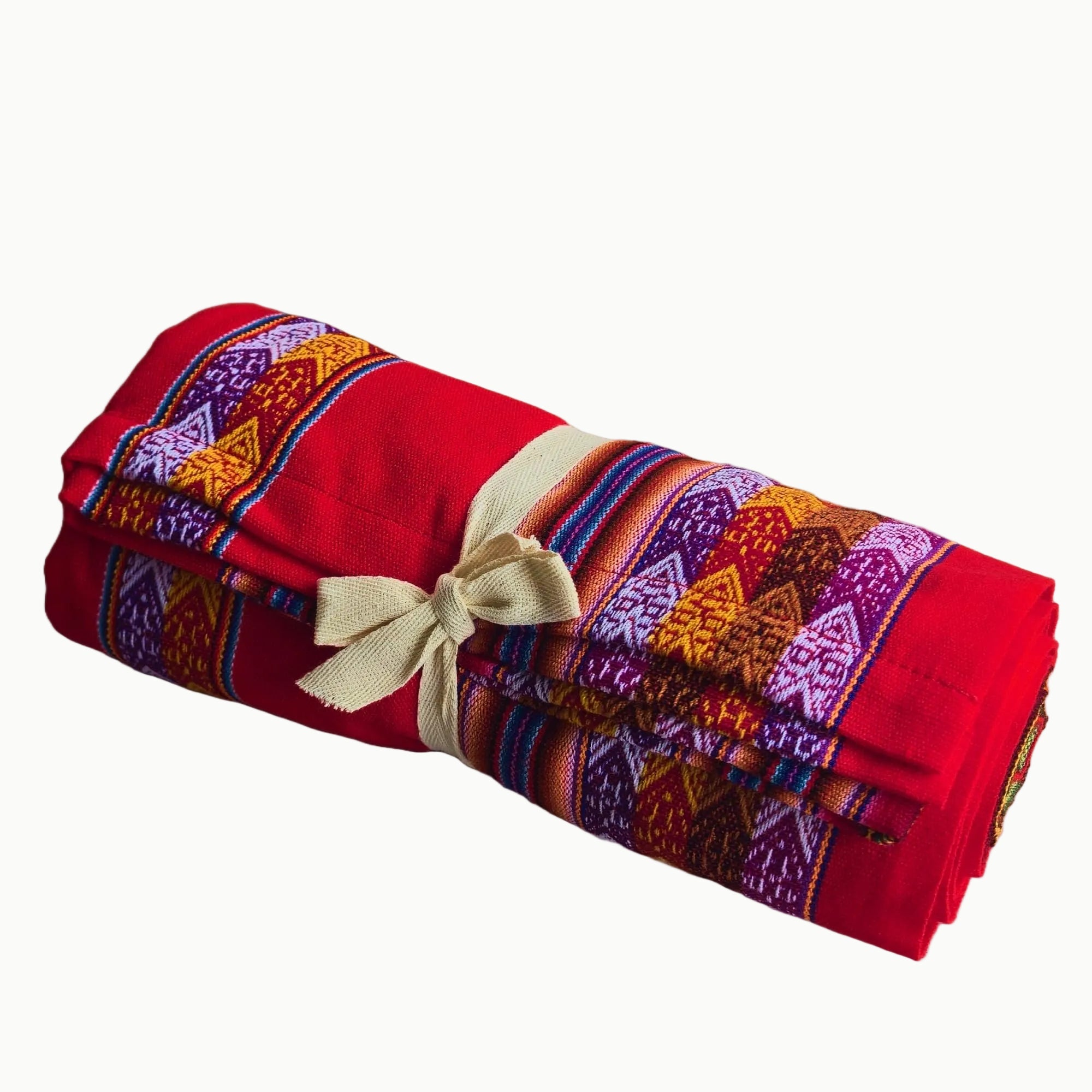 Folded red blanket with colorful patterns and a beige ribbon on a white background