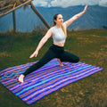 Woman practicing yoga on a colorful mat with mountains in the background