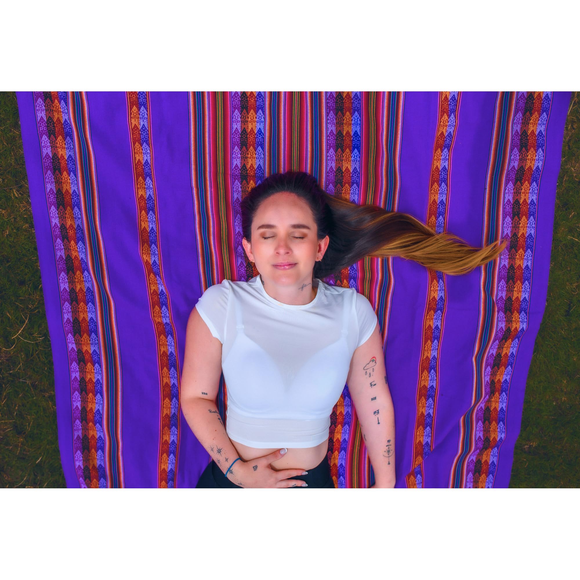 Person sitting on a colorful striped fabric with a purple background