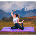 Woman practicing yoga on a colorful mat with mountains in the background